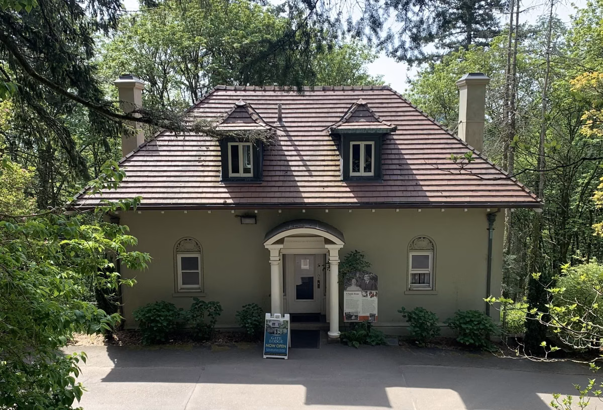 The Gate Lodge at Pittock Mansion, a small stucco house with dormer windows among trees