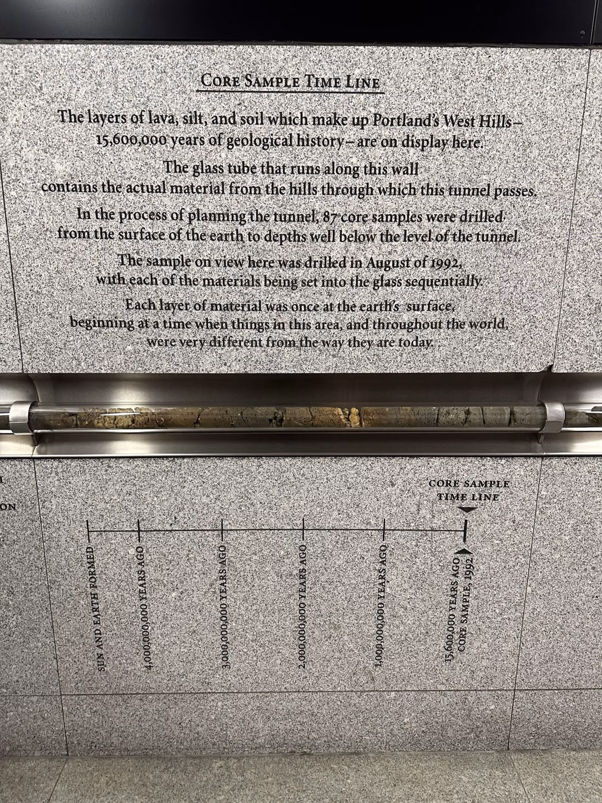 A granite wall panel in the Washington Park MAX station with a glass tube holding a rock core sample timeline