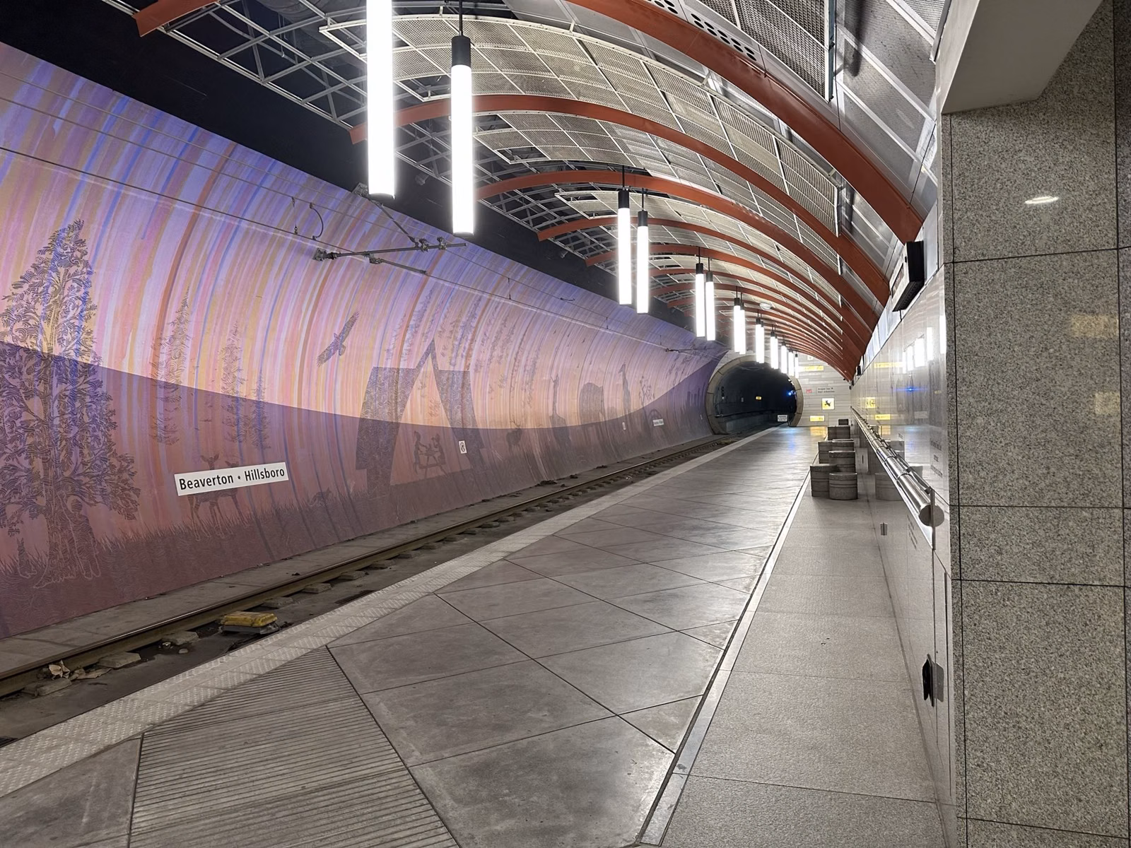 The underground platform of the Washington Park MAX light rail station in Portland, with a curved tunnel wall mural