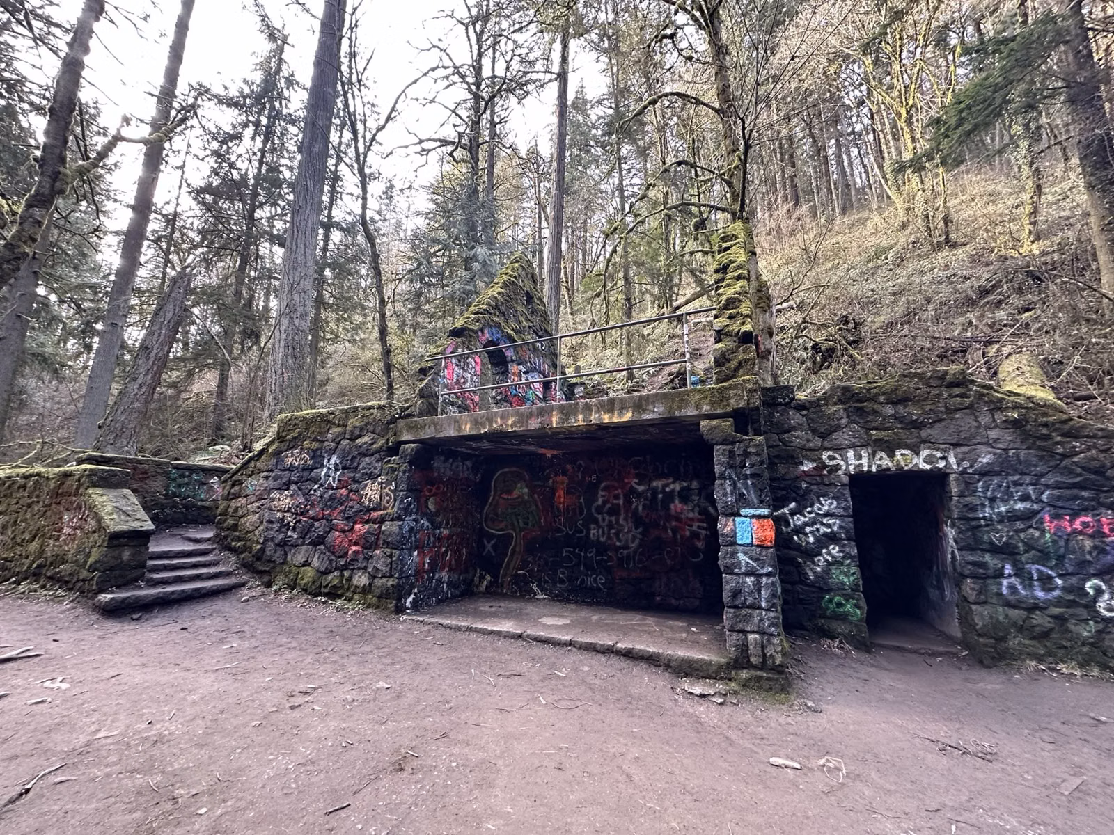The stone shell of the Stone House, known as the Witch's Castle, beside a dirt trail in Forest Park, Portland